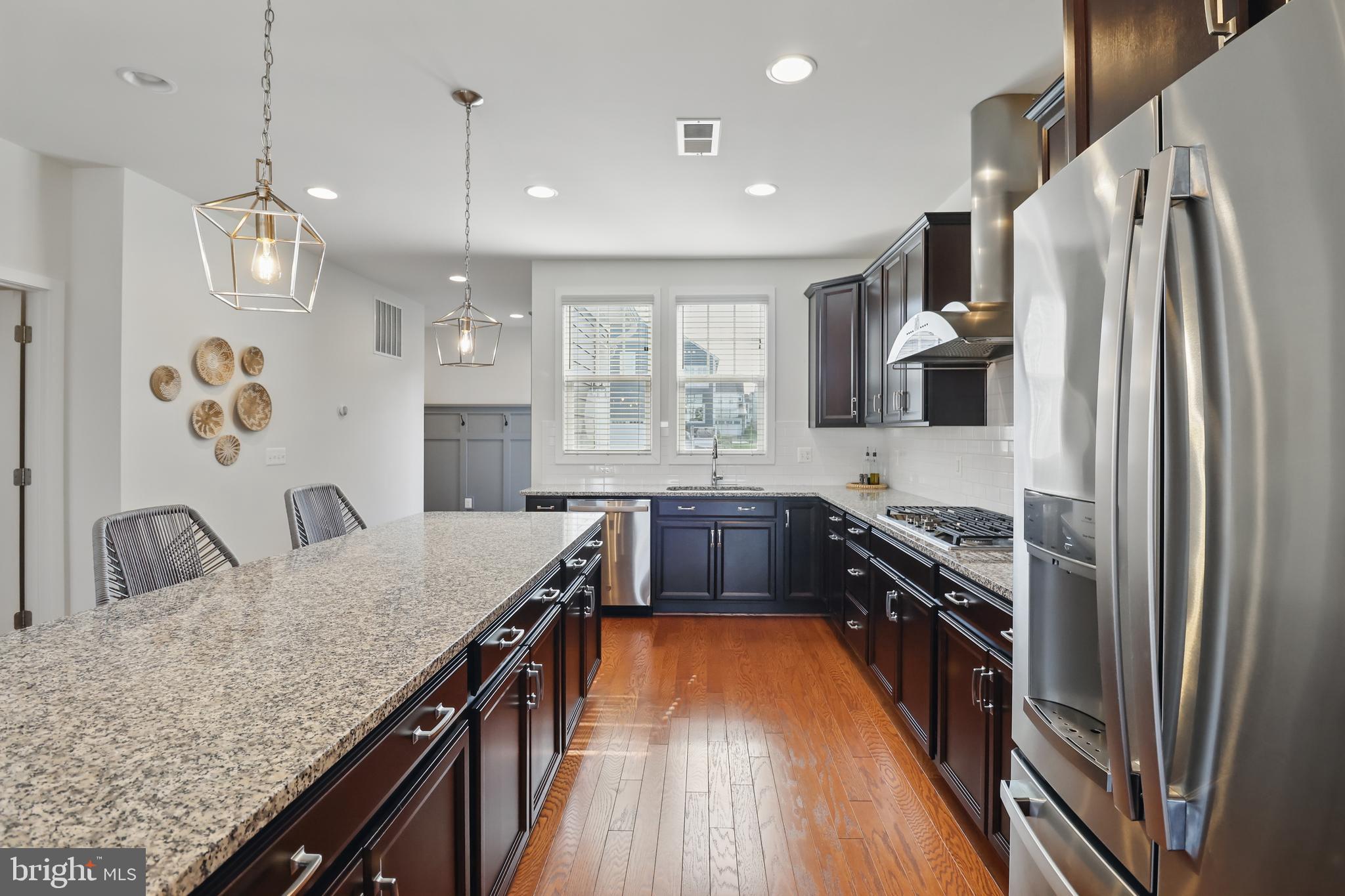 1010 Coubertin Drive Southeast Leesburg, VA 20175 - Photo 17 of 44 a kitchen with granite countertop a refrigerator a sink dishwasher a stove and white countertops with wooden floor