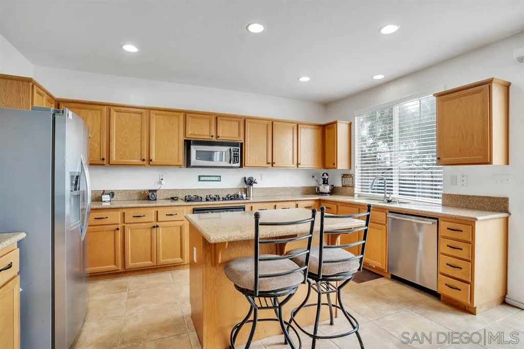 1103 Greenway Road Oceanside, CA 92057 - Photo 6 of 25 a kitchen with stainless steel appliances granite countertop a stove top oven a sink dishwasher and a refrigerator with wooden cabinets