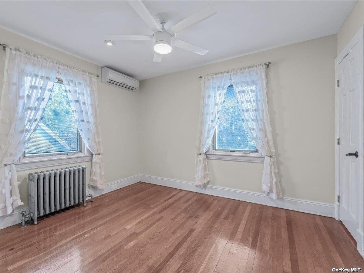 33-71 161st Street Queens, NY 11358 - Photo 21 of 35 wooden floor in an empty room with a window