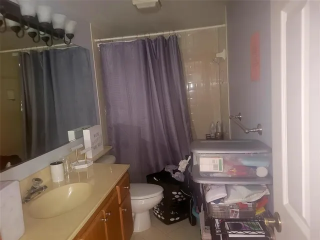 a bathroom with a sink a toilet and shower curtain