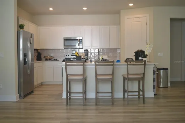 a kitchen with a sink a refrigerator and chairs