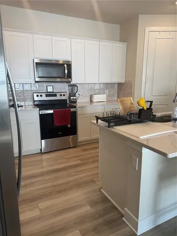 a kitchen with stainless steel appliances a stove a sink and a microwave