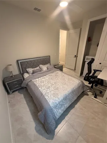 a bedroom with a bed a couch and a flat tv screen on the dresser