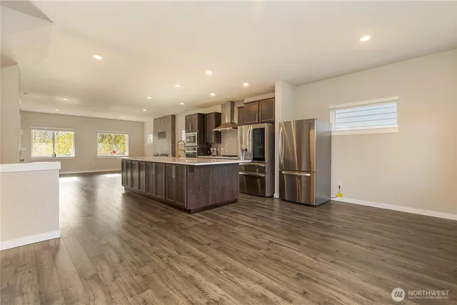 a kitchen with stainless steel appliances a refrigerator and wooden floors