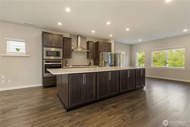 a kitchen with kitchen island granite countertop wooden floors and stainless steel appliances