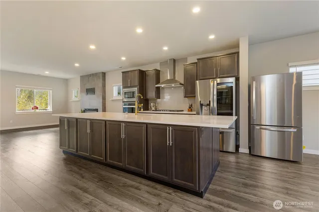 a kitchen with stainless steel appliances a refrigerator and wooden floors