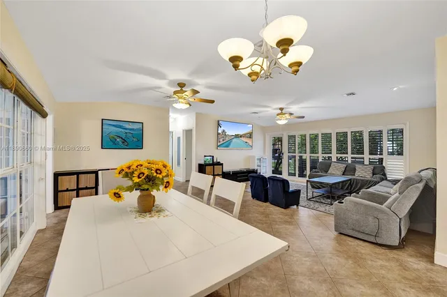 a living room with couches chandelier furniture and a potted plant