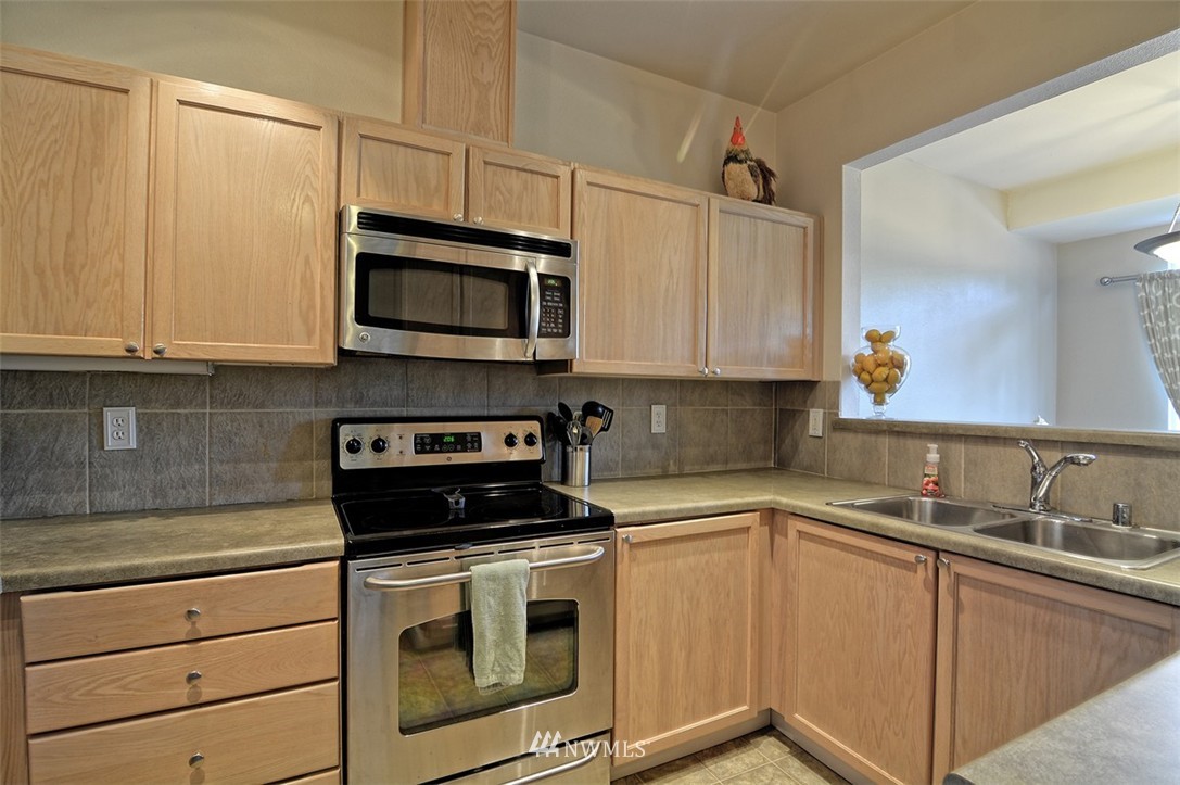 18930 Bothell Everett Highway, Unit M105 Bothell, WA 98012 - Photo 5 of 19 a kitchen with granite countertop white cabinets stainless steel appliances and a sink