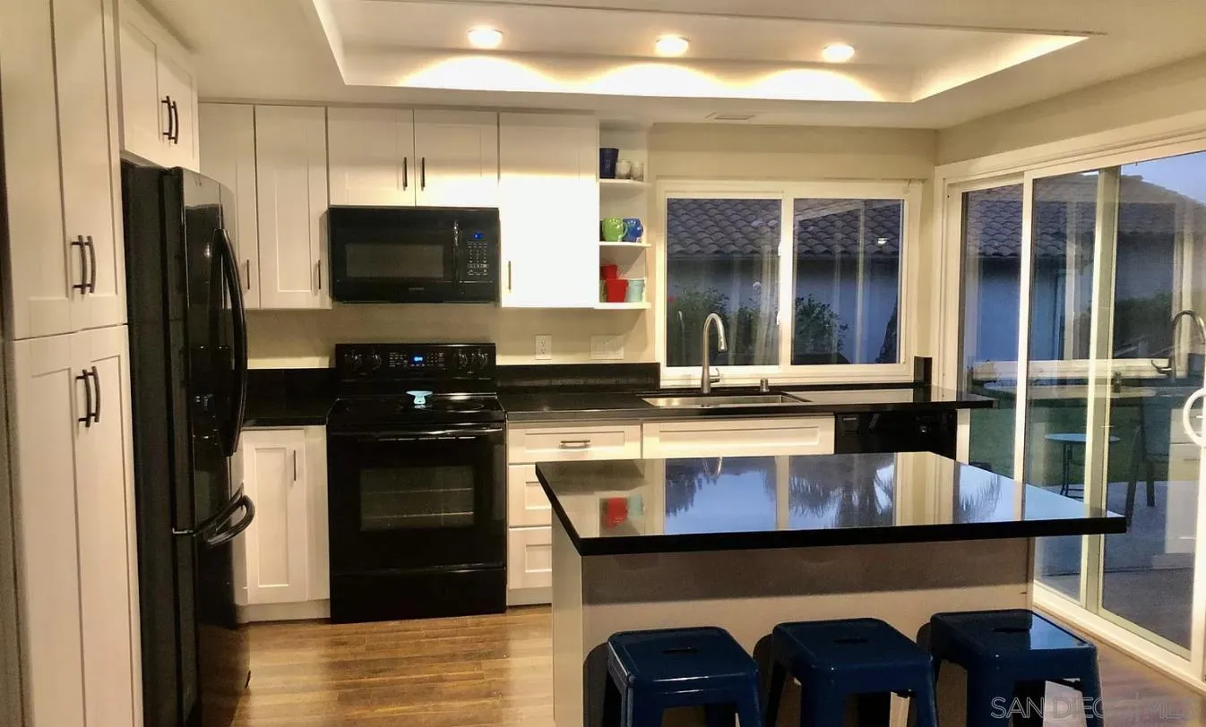 660 San Mario Drive Solana Beach, CA 92075 - Photo 6 of 25 a kitchen with a table chairs refrigerator and cabinets