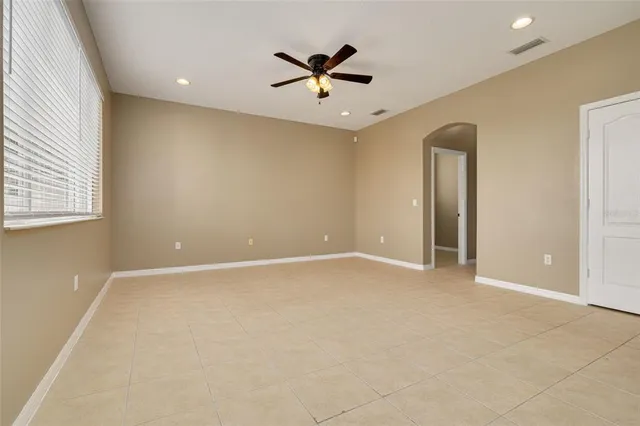 an empty room with window and ceiling fan