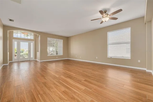 a view of an empty room with a window and wooden floor