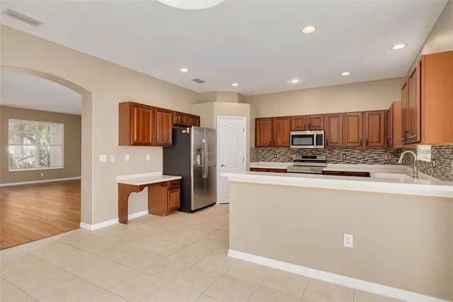 a large kitchen with stainless steel appliances kitchen island granite countertop a refrigerator and a stove top oven with wooden floor