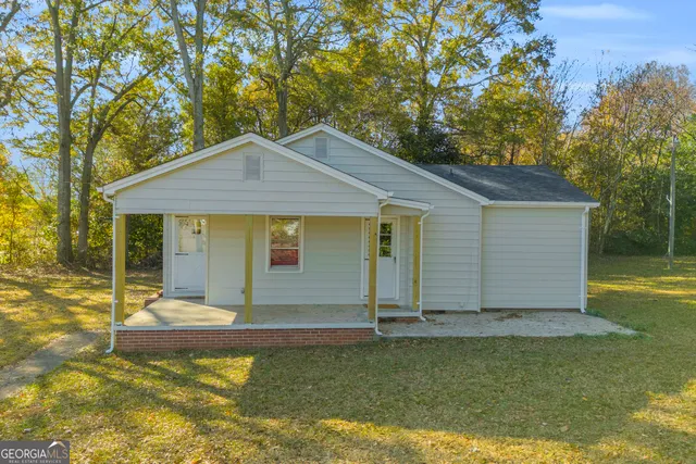 a front view of house with yard and trees in the background