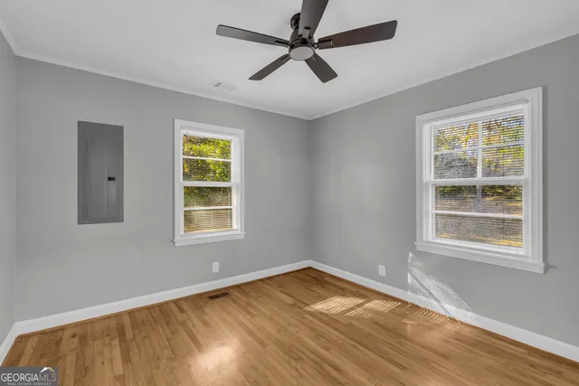 a view of empty room with wooden floor and fan