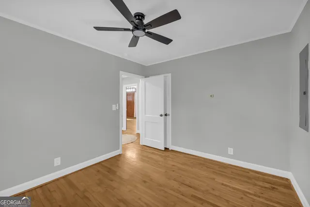 an empty room with wooden floor and a ceiling fan