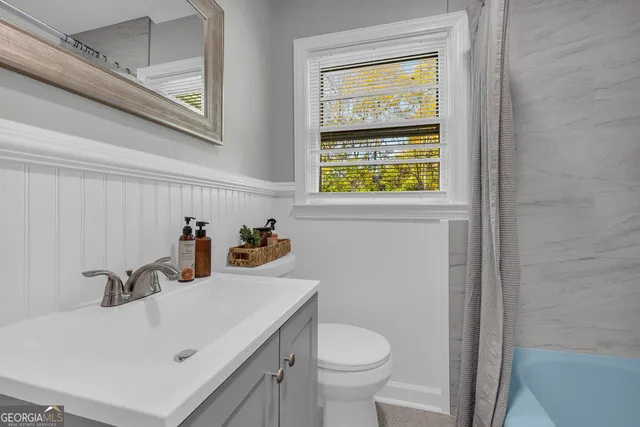 a bathroom with a sink a toilet and a window