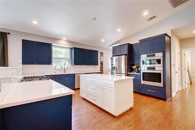 a large kitchen with stainless steel appliances wooden cabinets and a sink