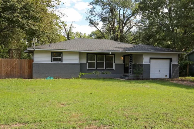 a front view of house with yard and trees in the background