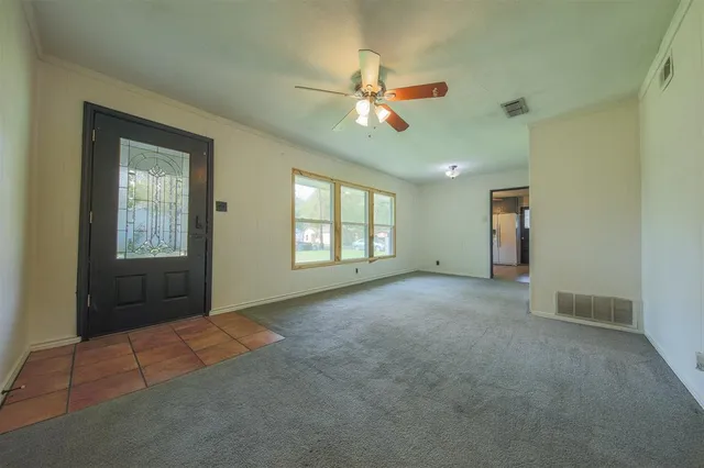 an empty room with windows and fan