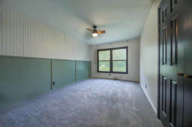 a view of an empty room with a chandelier fan