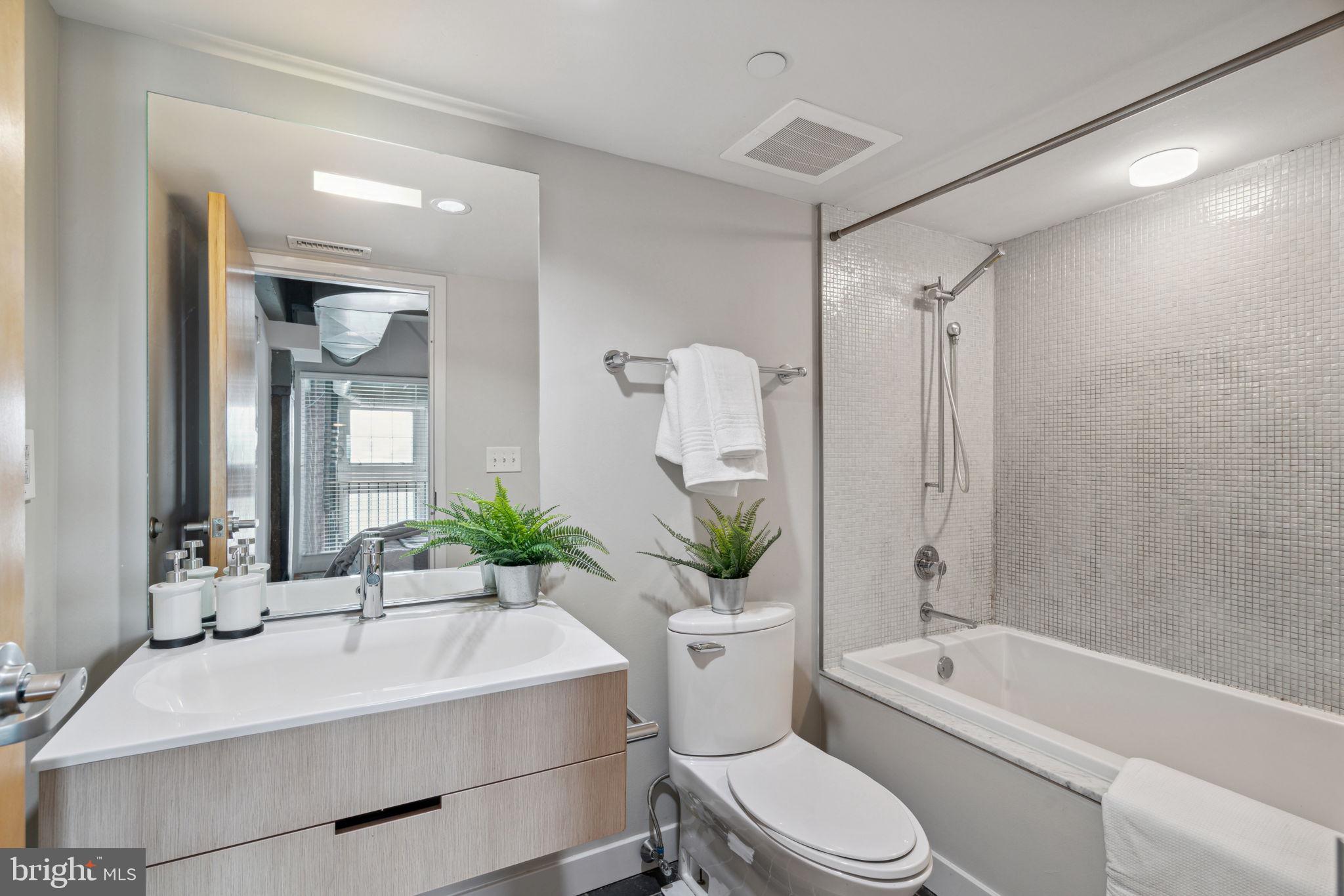 a bathroom with a white bath tub a mirror a toilet and a sink