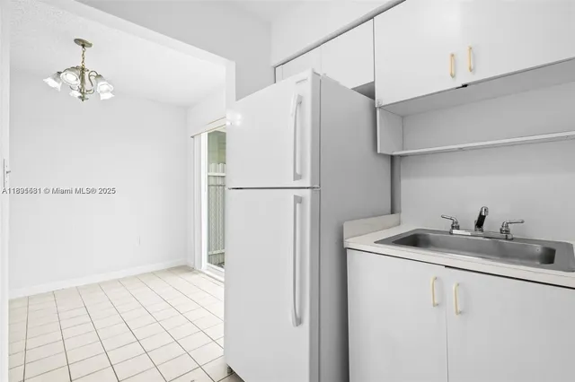 a kitchen with white cabinets and refrigerator