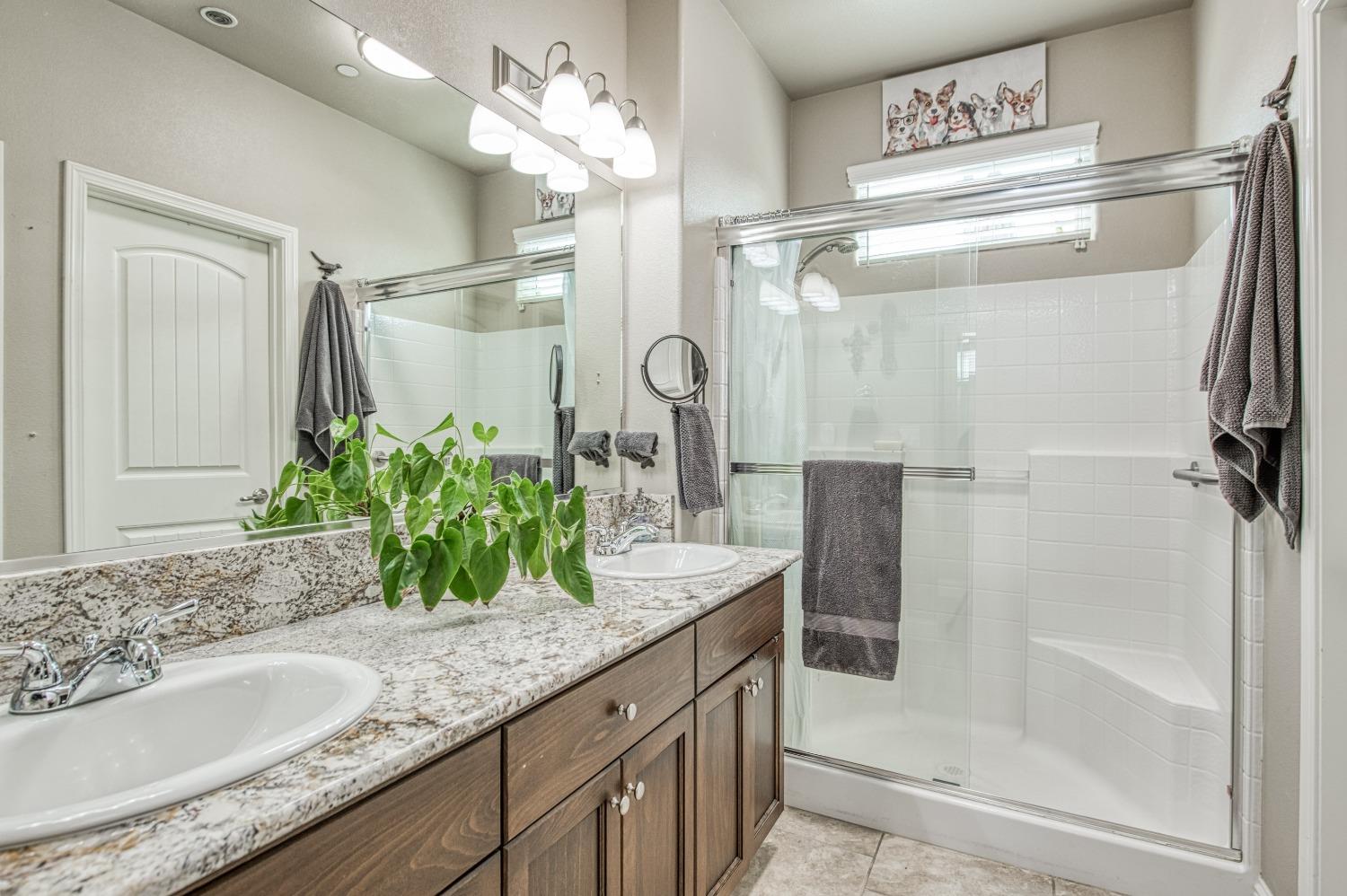 3479 Park Avenue Clovis, CA 93611 - Photo 9 of 27 a bathroom with a granite countertop sink a mirror and a shower