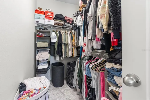 a view of walk in closet with clothes and shoes