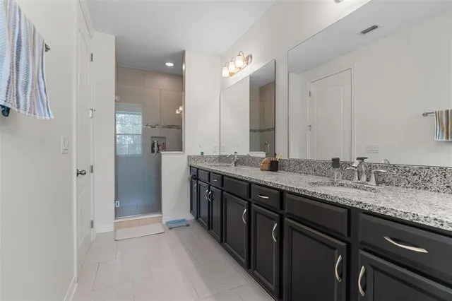 a bathroom with a granite countertop sink double vanity and a mirror