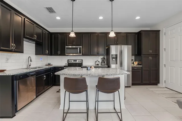 a kitchen with stainless steel appliances granite countertop a refrigerator a sink a stove a microwave and wooden cabinets