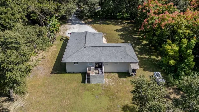 an aerial view of residential house with outdoor space and trees all around