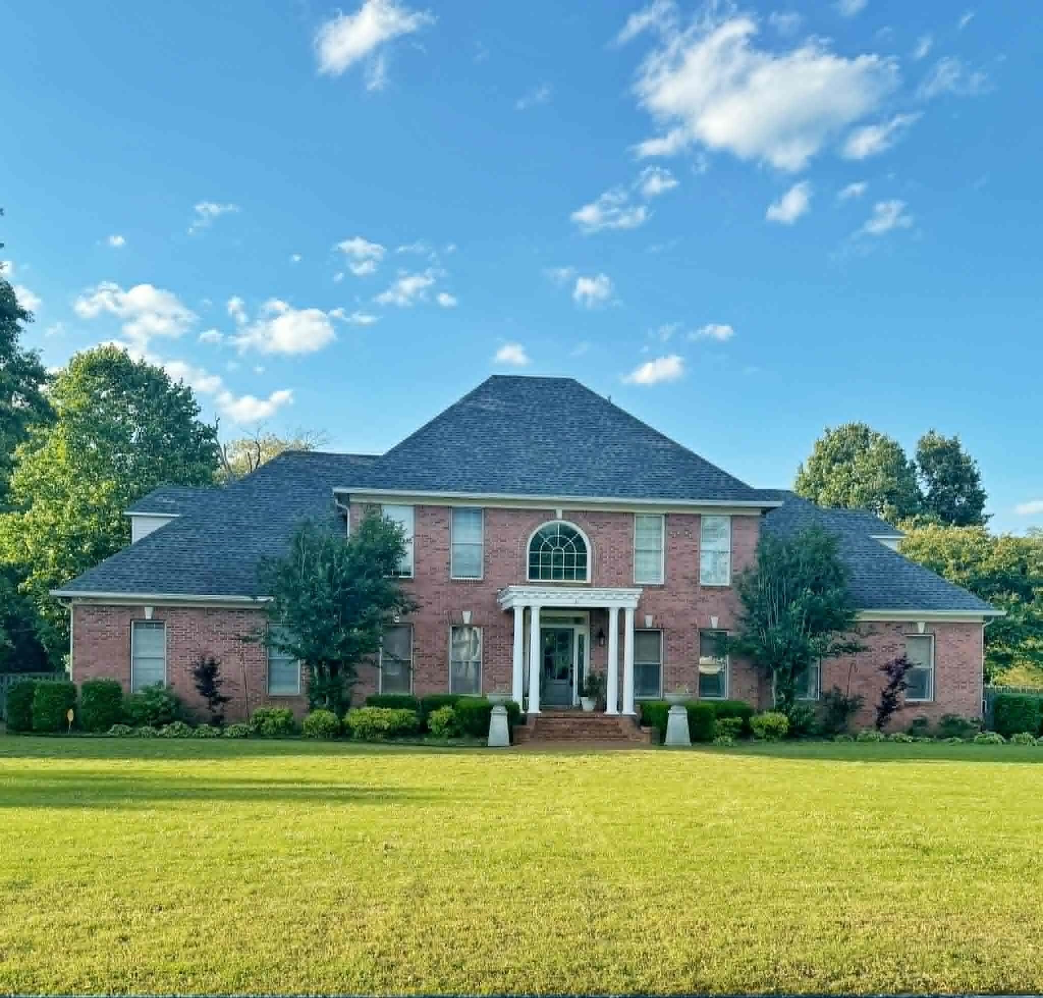 37 Crownpointe Cove Jackson, TN 38305 - Photo 1 of 39 Expansive front lawn leading to a brick facade residence featuring a prominent portico with white columns, an arched transom window, and a dark shingled roof