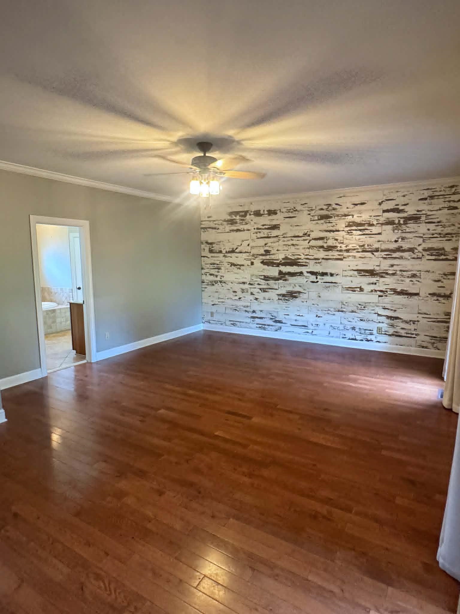 37 Crownpointe Cove Jackson, TN 38305 - Photo 16 of 39 Spacious room featuring wood-finish flooring, a decorative accent wall, ceiling fan with integrated lighting, and crown molding
