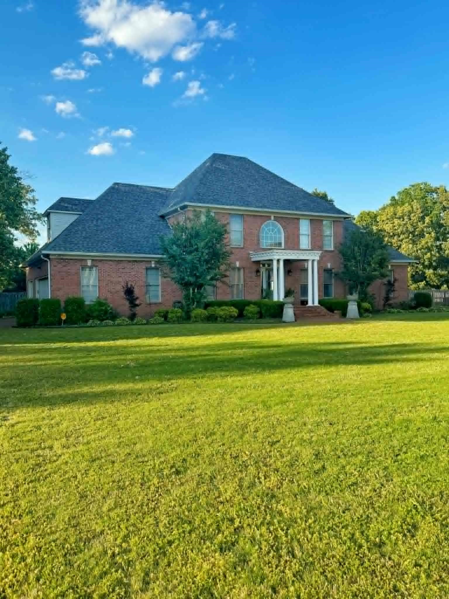 37 Crownpointe Cove Jackson, TN 38305 - Photo 2 of 39 Traditional brick residence featuring a prominent portico with white columns, a large arched window, and a dark shingle roof