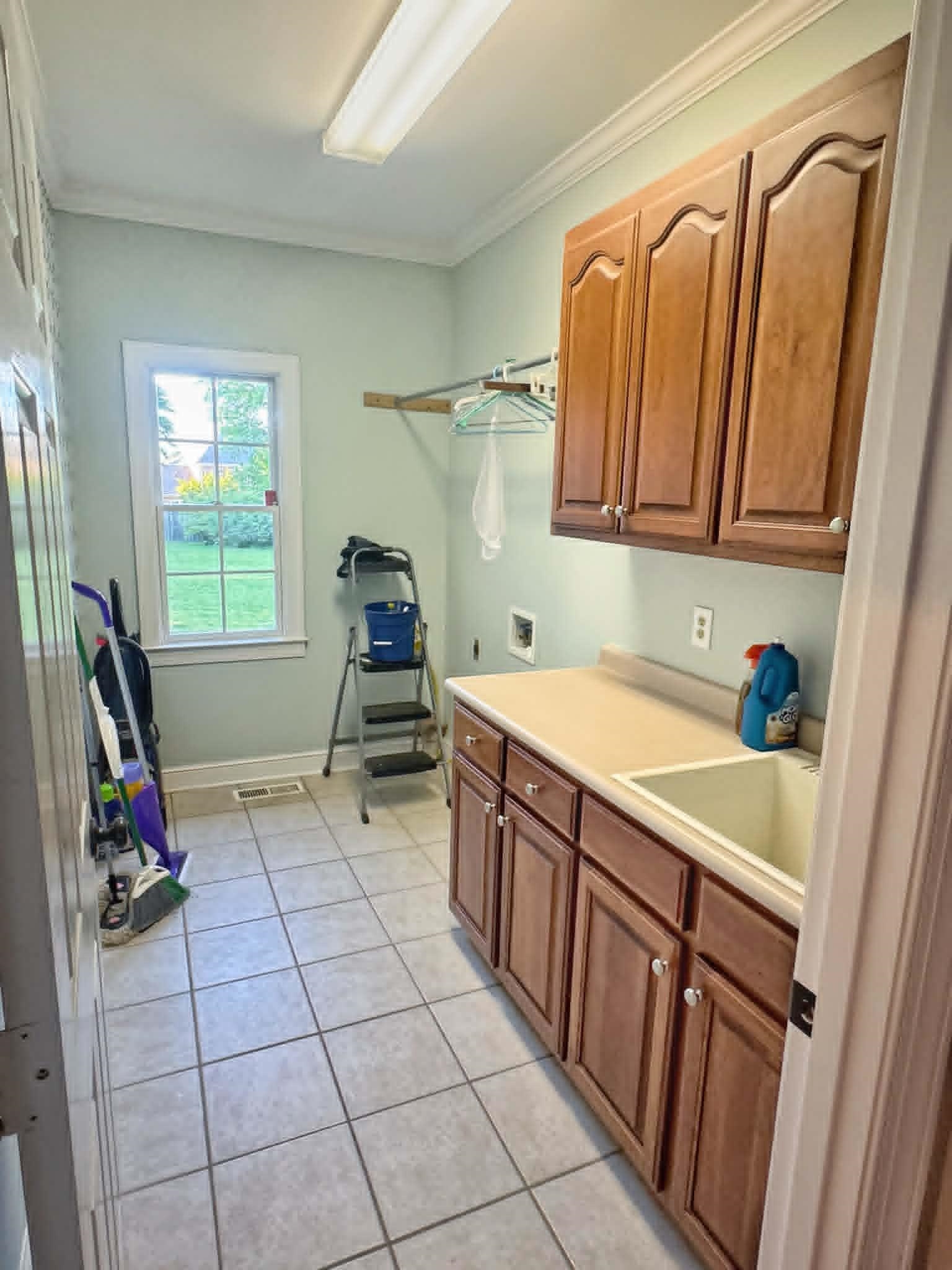 37 Crownpointe Cove Jackson, TN 38305 - Photo 22 of 39 Laundry room featuring a utility sink, wood cabinetry, light countertop, and tiled flooring