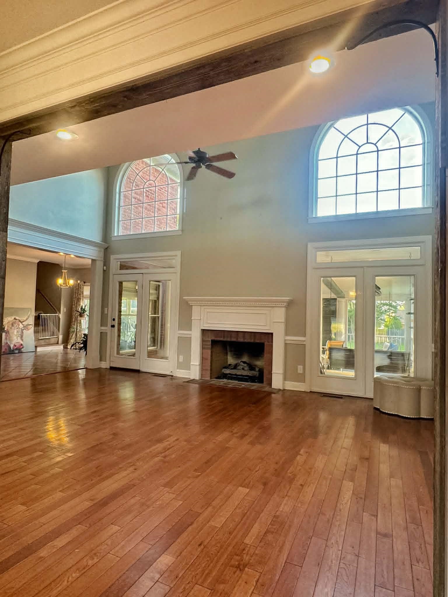 37 Crownpointe Cove Jackson, TN 38305 - Photo 8 of 39 Spacious living area featuring high ceilings, wood-finish flooring, a brick fireplace with a white mantel, and multiple arched windows