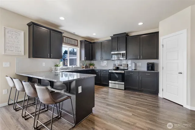 a kitchen with granite countertop a stove top oven a sink dishwasher a dining table and chairs with wooden floor