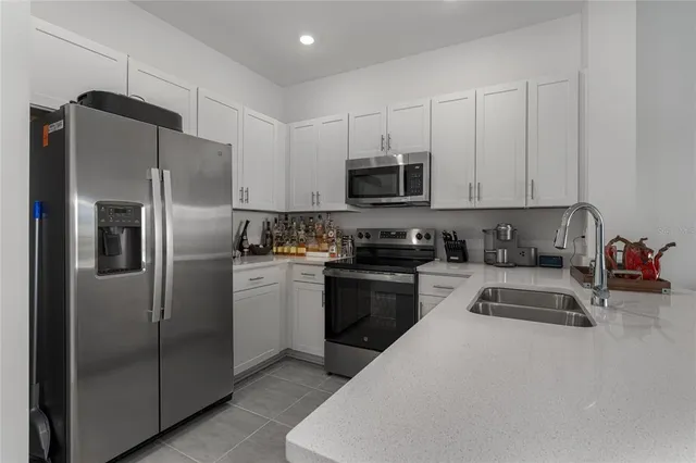 a kitchen with refrigerator a microwave a sink and cabinets