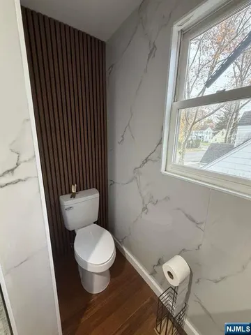 a white toilet sitting in a bathroom next to a window