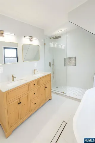 a spacious bathroom with a double vanity sink a mirror and a bathtub