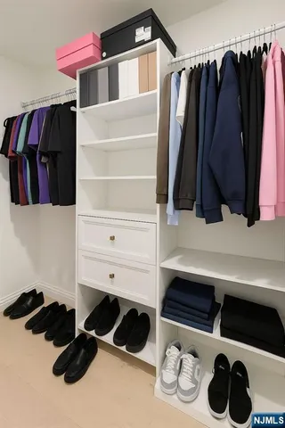 a view of walk in closet with clothes and shoes