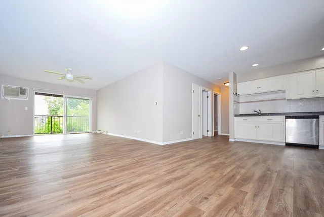 a view of an empty room with a window and wooden floor