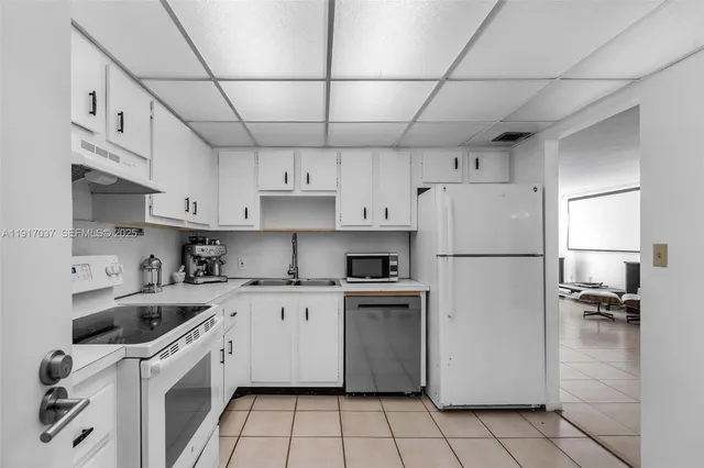 a kitchen with cabinets a sink and white appliances