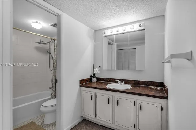 a bathroom with a granite countertop sink toilet and shower