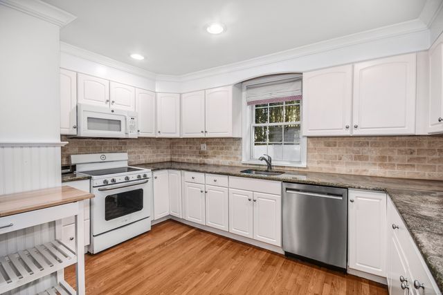 a kitchen with cabinets stainless steel appliances and wooden floor
