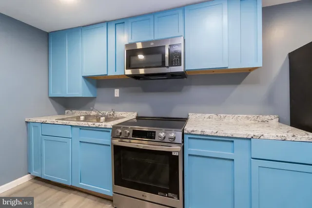 a kitchen with granite countertop a stove and a microwave with wooden floor