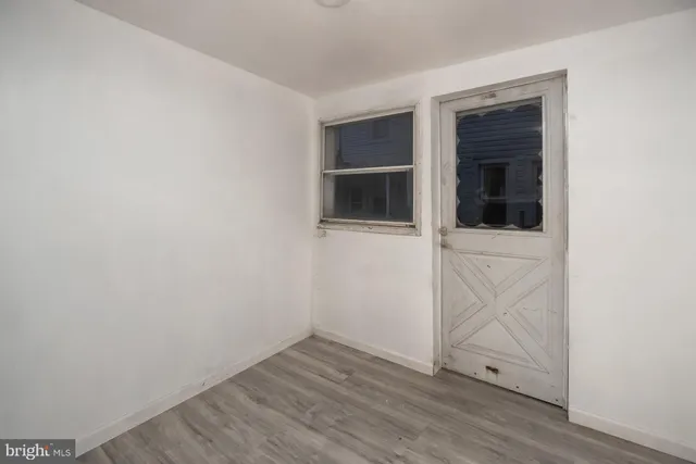 a view of an empty room with wooden floor and closet