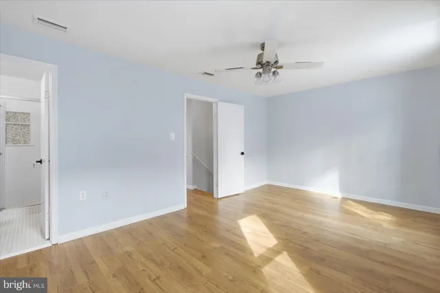 an empty room with windows and fan