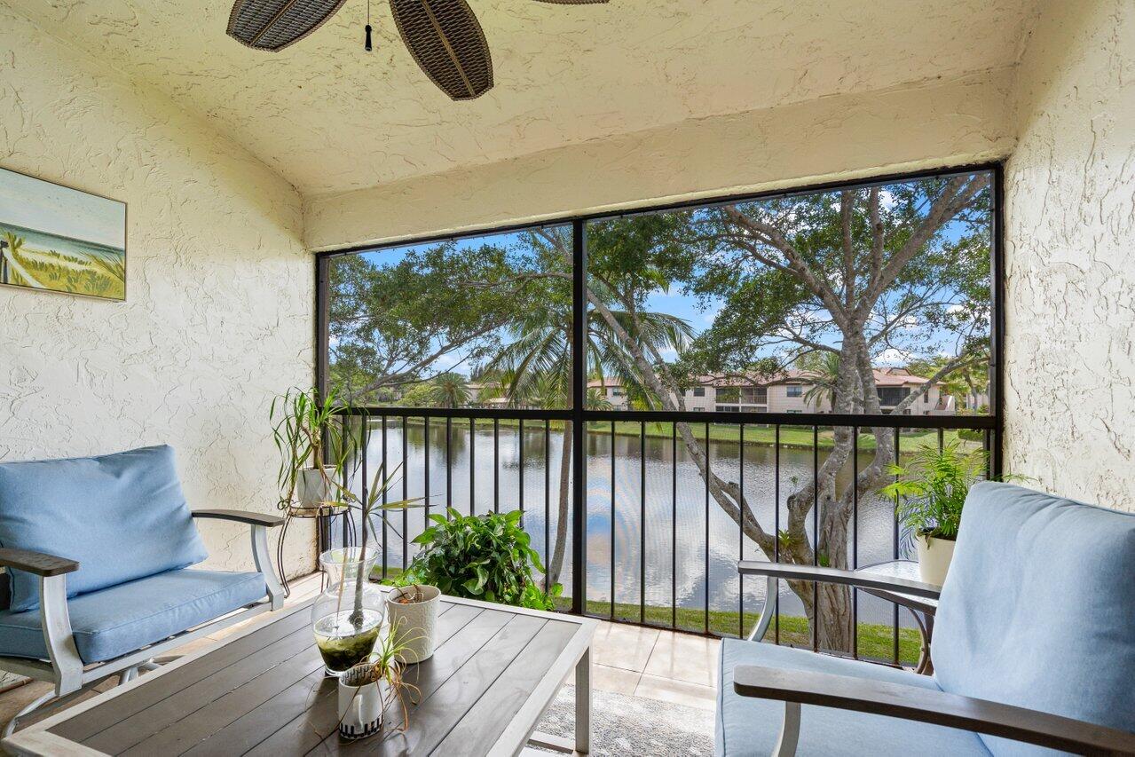 9261 Vista Del Lago, Unit H Boca Raton, FL 33428 - Photo 22 of 27 a living room with large windows and a table
