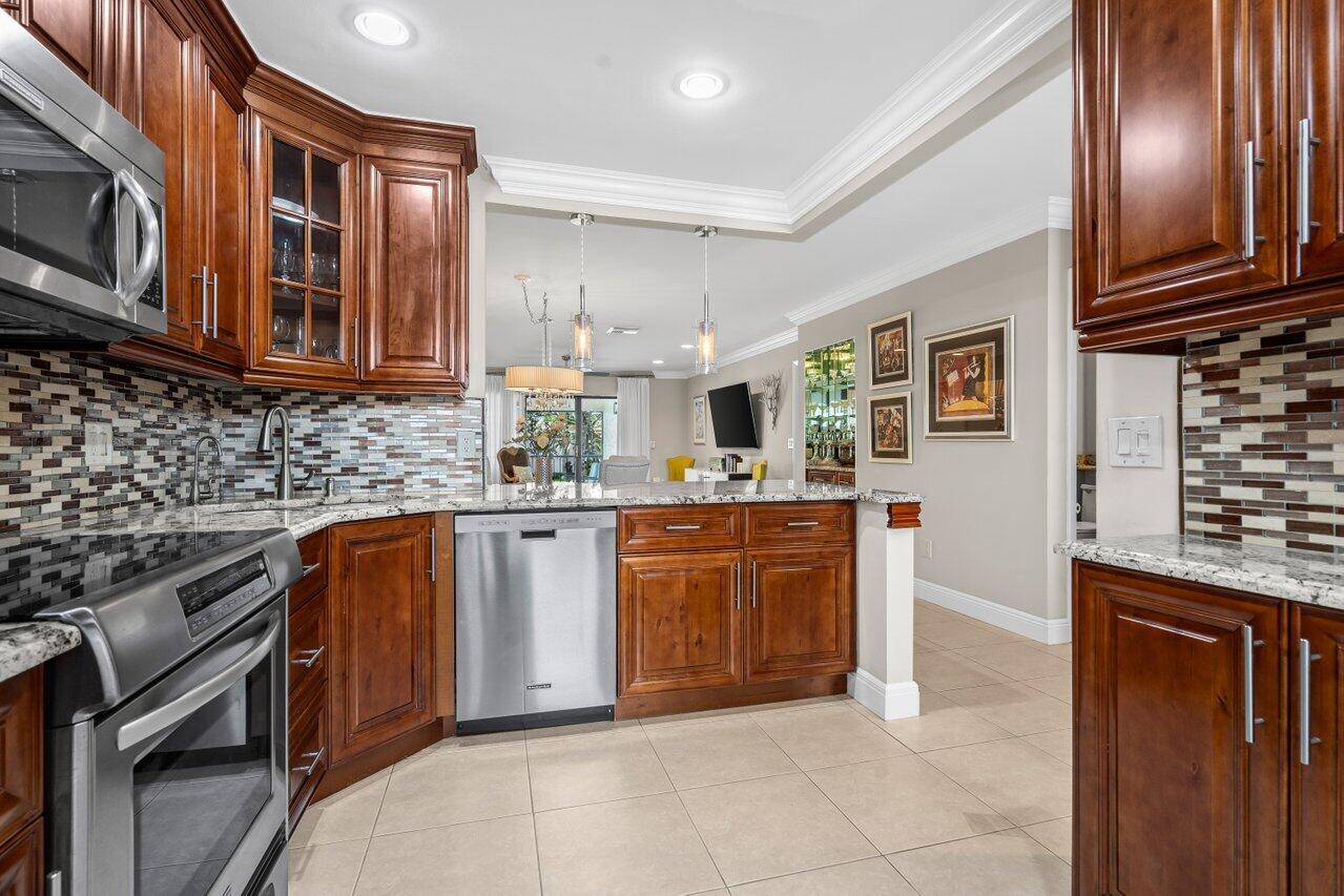 9261 Vista Del Lago, Unit H Boca Raton, FL 33428 - Photo 6 of 27 a kitchen with stainless steel appliances granite countertop a stove top oven a sink dishwasher and cabinets